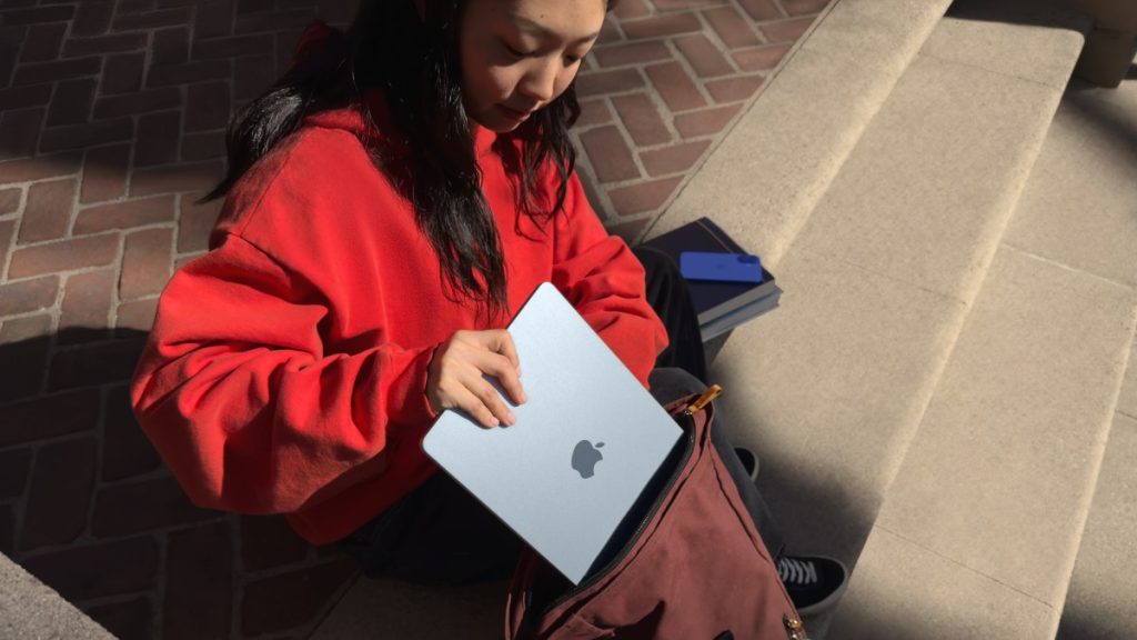young woman putting Apple MacBook Air into a satchel