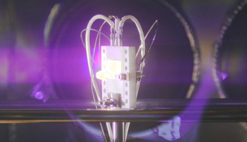 A radiovoltaic material glows under bombardment by alpha particles.