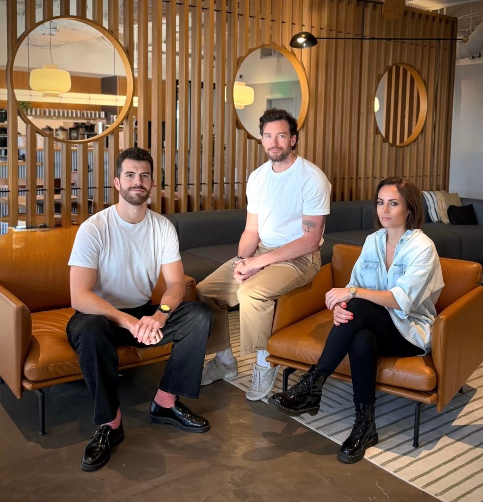 Origin Lab raises $8M to help video game companies sell data to world-model builders Two men and a woman sit on leather chairs in a well appointed office space.